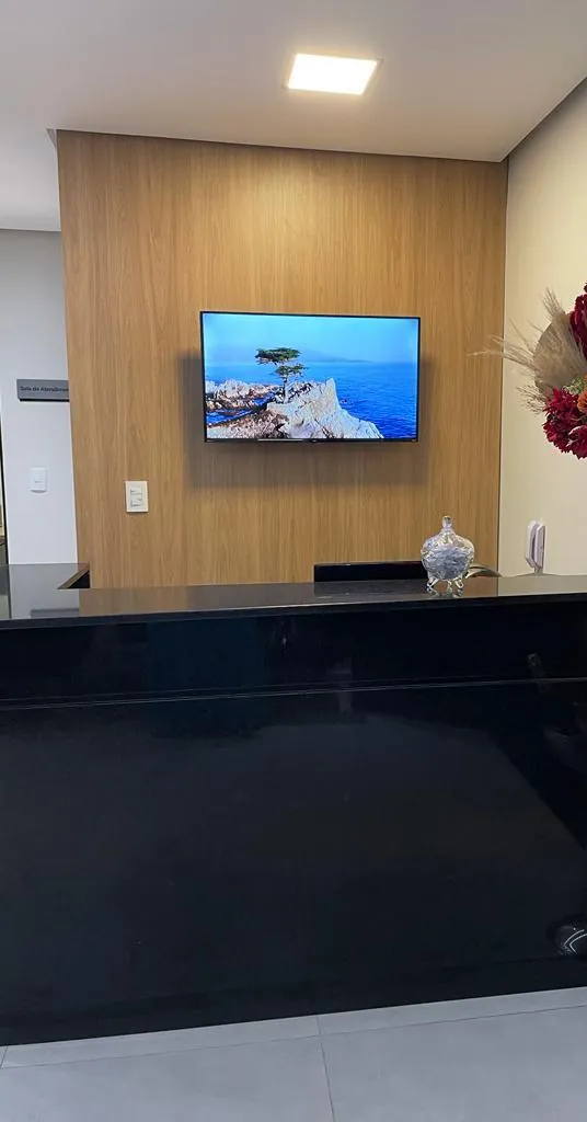 Recepção com balcão preto e painel de madeira.