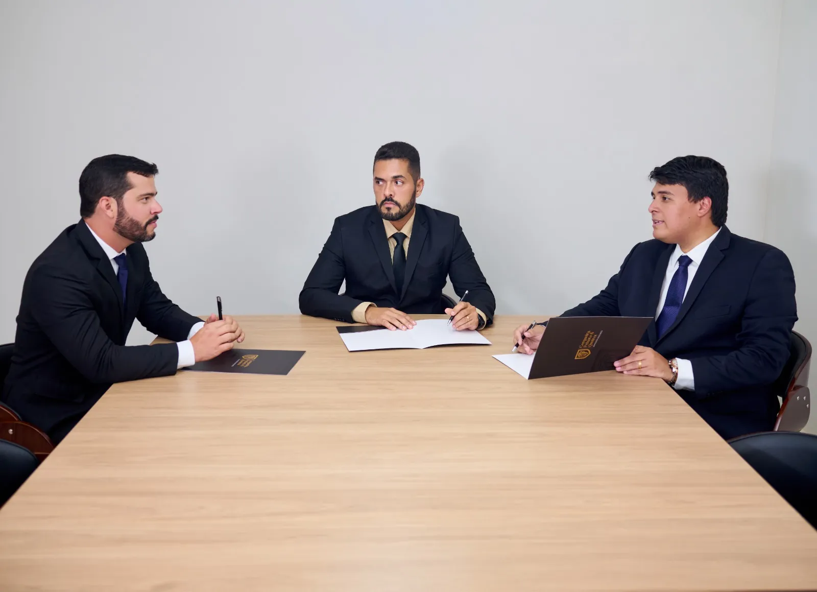 Os três sócios reunidos à mesa, em conversa de trabalho.